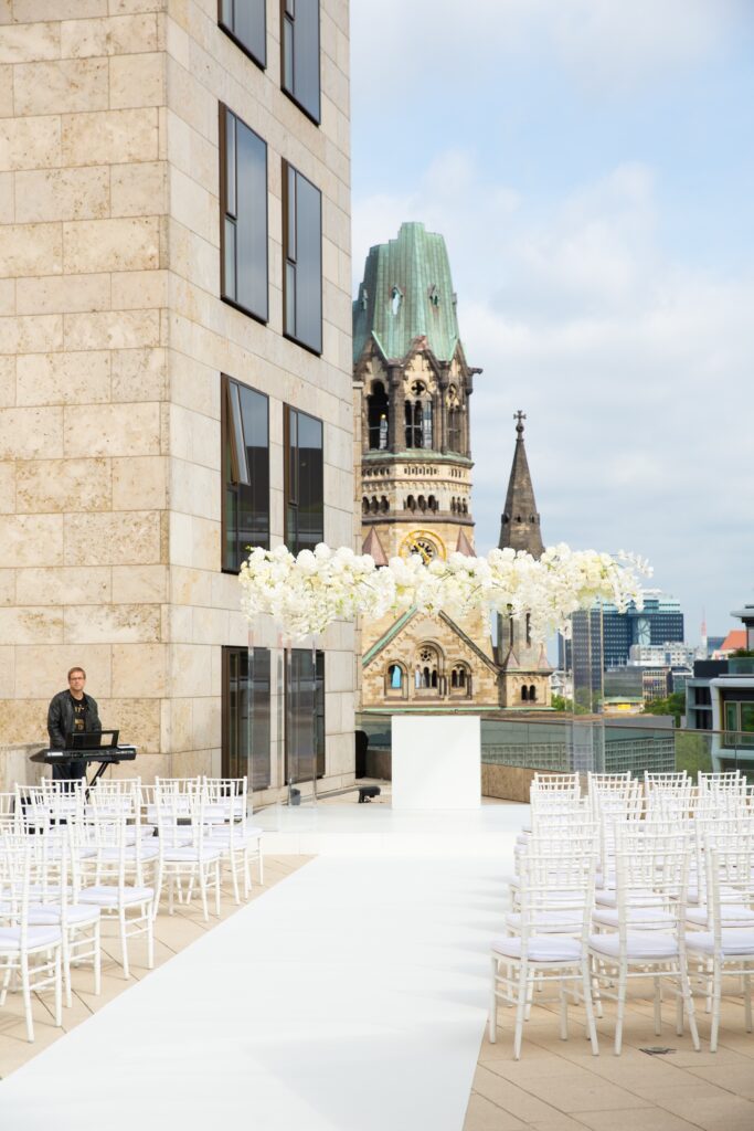 Stühle und Traubogen aus weißen Blumen auf der Dachterrasse des Waldorf Astoria in Berlin
